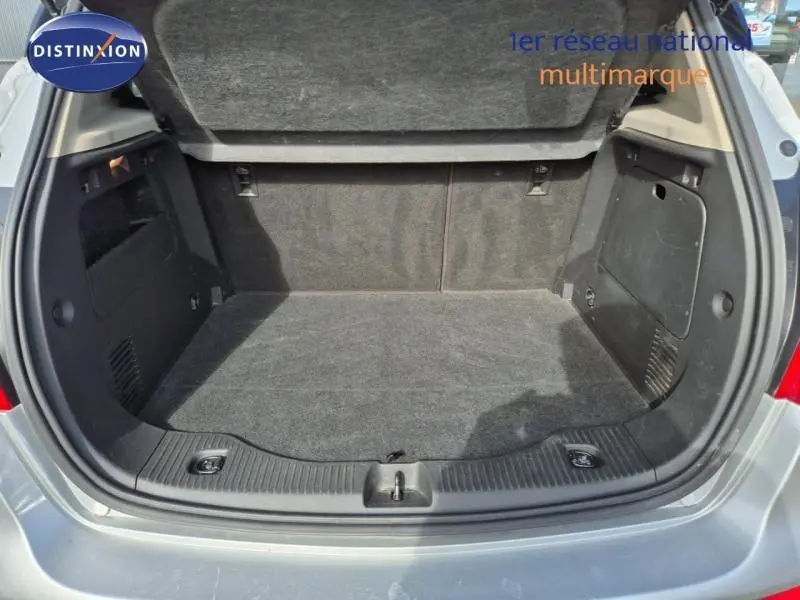 Coffre ouvert vu de l'arrière d'un Opel Mokka X gris minéral, montrant un espace de chargement propre et spacieux.