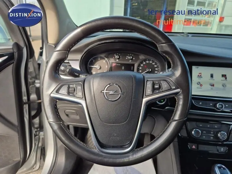 Vue intérieure centrée sur le volant cuir multifonction de l'Opel Mokka X gris minéral avec tableau de bord et écran tactile.