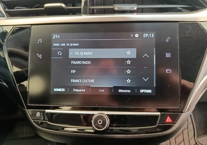 Écran tactile central de l’Opel Corsa blanc 2022 affichant la liste des radios, vue rapprochée intérieure.