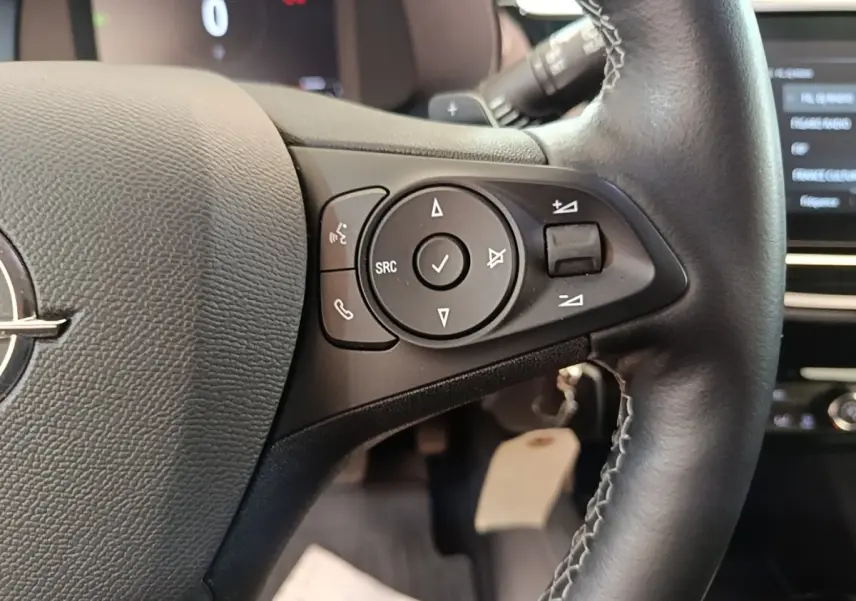 Gros plan sur le volant cuir multifonctions de l'Opel Corsa 2022, avec commandes audio et téléphone intégrées.