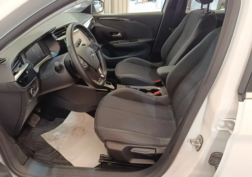 Vue intérieure côté conducteur d'une Opel Corsa blanche 2022, volant cuir multifonctions et sièges tissu noirs.