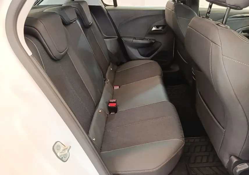 Vue intérieure côté gauche de la banquette arrière noire de l'Opel Corsa blanche, avec appuie-têtes et ceintures visibles.