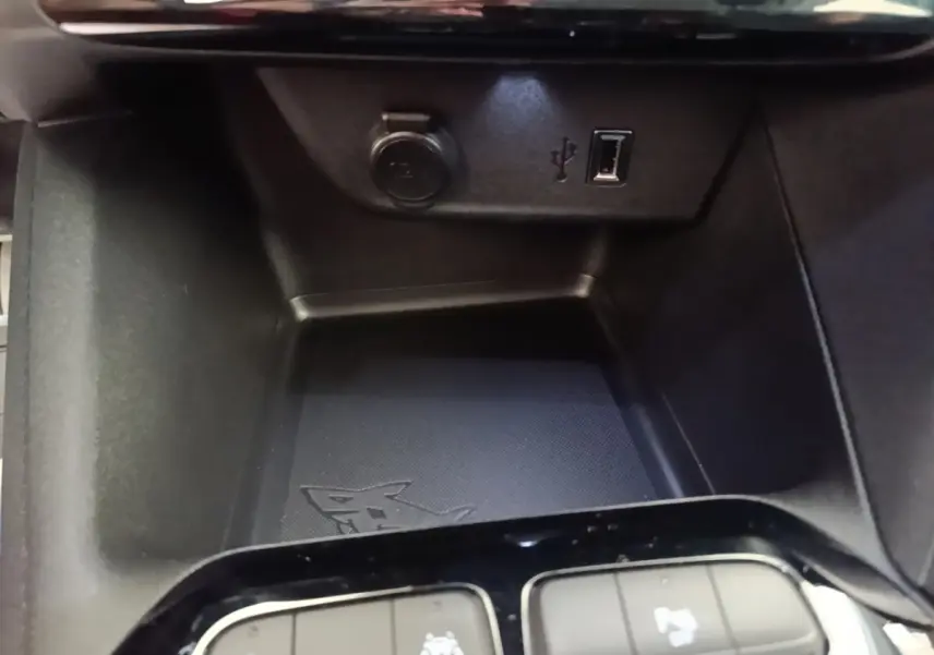 Gros plan sur la console centrale de l’Opel Corsa blanche, avec prise USB et prise 12V visibles.