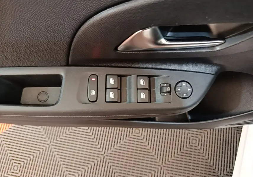 Vue rapprochée de la commande des vitres et des rétroviseurs sur la porte côté conducteur d'une Opel Corsa blanche.