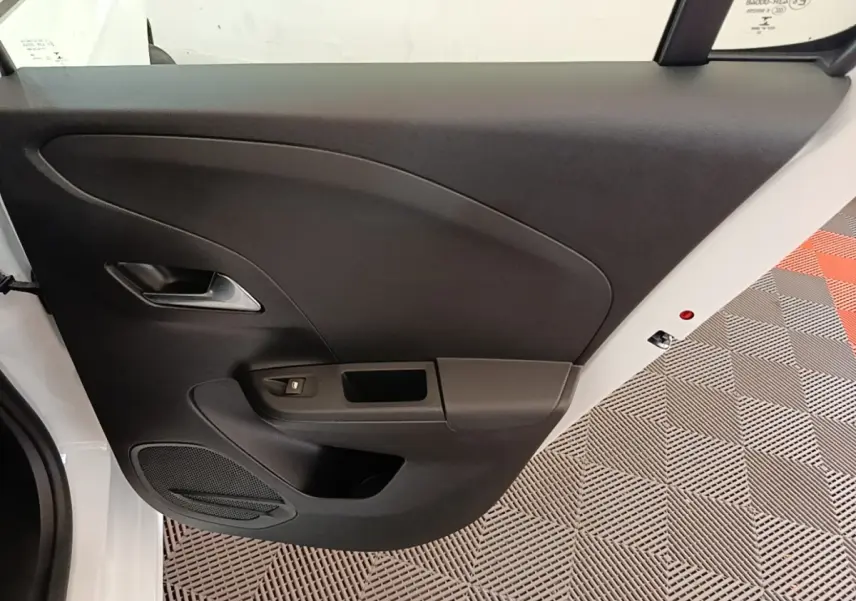 Vue intérieure de la porte avant gauche noire d'une Opel Corsa blanche, avec poignée argentée et commande de vitre.
