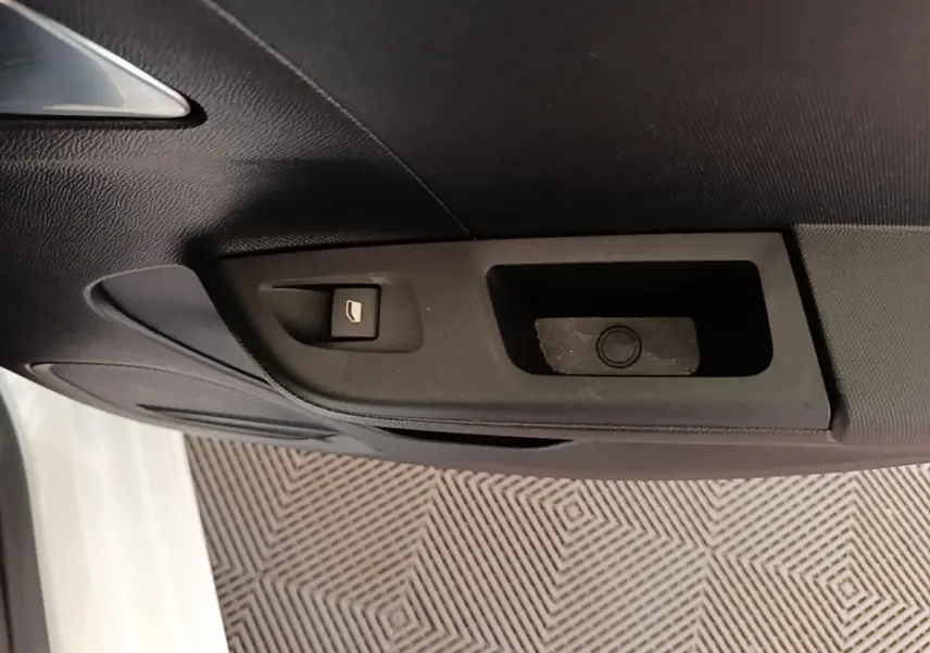 Gros plan sur la commande de lève-vitre côté conducteur d’une Opel Corsa blanche, intérieur noir.