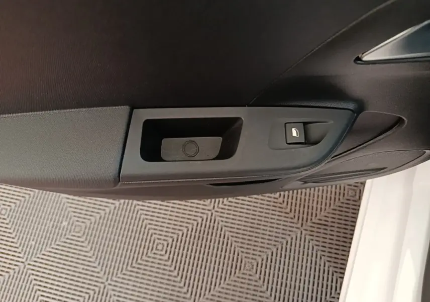 Gros plan sur la poignée intérieure de porte côté conducteur d’une Opel Corsa blanche, avec bouton de verrouillage.
