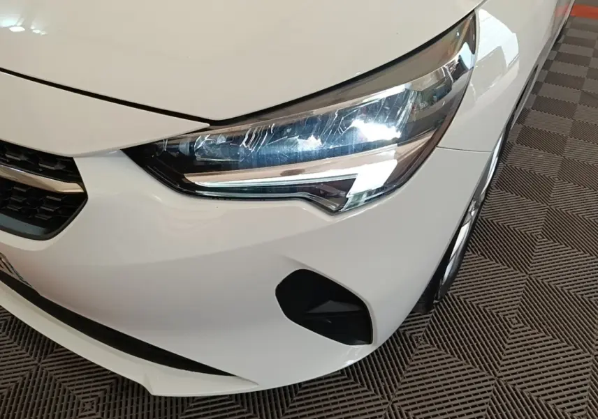 Gros plan sur l'avant droit blanc d'une Opel Corsa 2022, mettant en valeur le phare LED et la calandre.