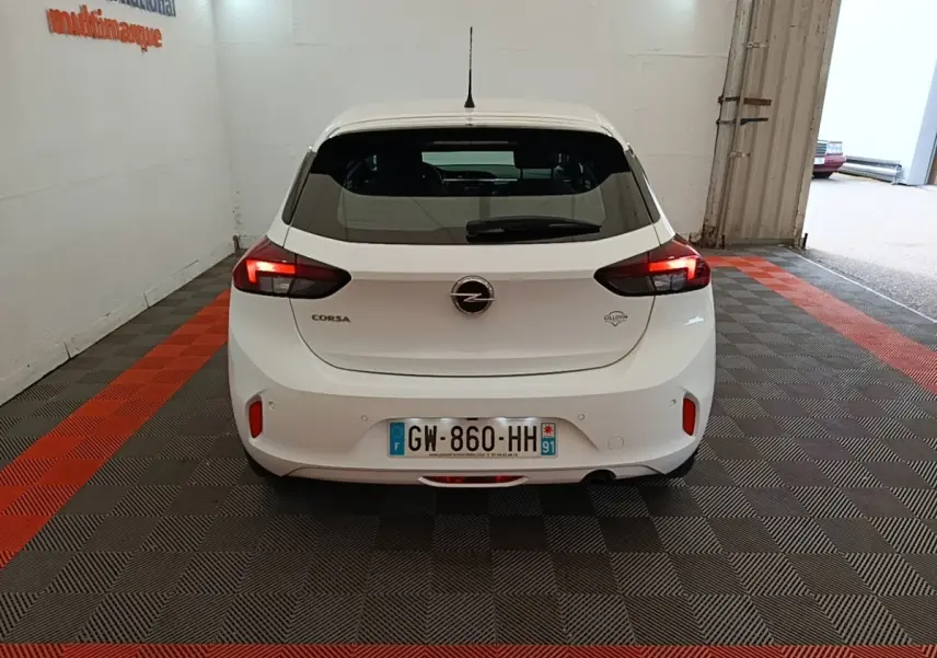 Vue arrière d'une Opel Corsa blanche 2022 avec feux LED allumés, stationnée sur un sol à damier gris et rouge.