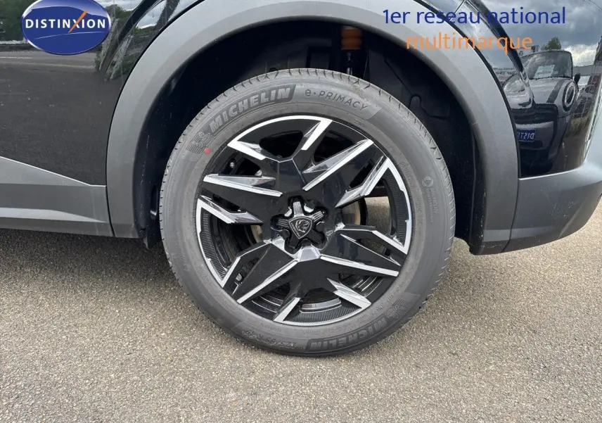 Gros plan sur la roue avant gauche du Peugeot 3008 Hybrid 2025 noir perle métal avec jante alliage noire et argentée design moderne.