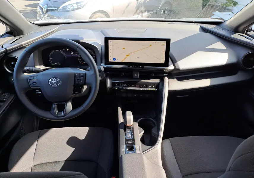 Vue plongeante sur l'intérieur du Toyota C-HR gris minéral, montrant la console centrale et les sièges avant en tissu noir.