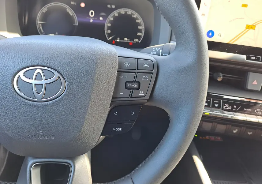 Gros plan sur la manette d'éclairage à gauche du volant du Toyota C-HR gris minéral, tableau de bord numérique visible.