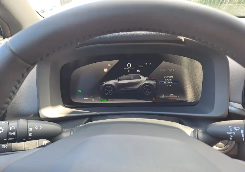 Détail intérieur côté gauche du tableau de bord noir du Toyota C-HR gris minéral 2025 avec commandes des rétroviseurs et ventilation.