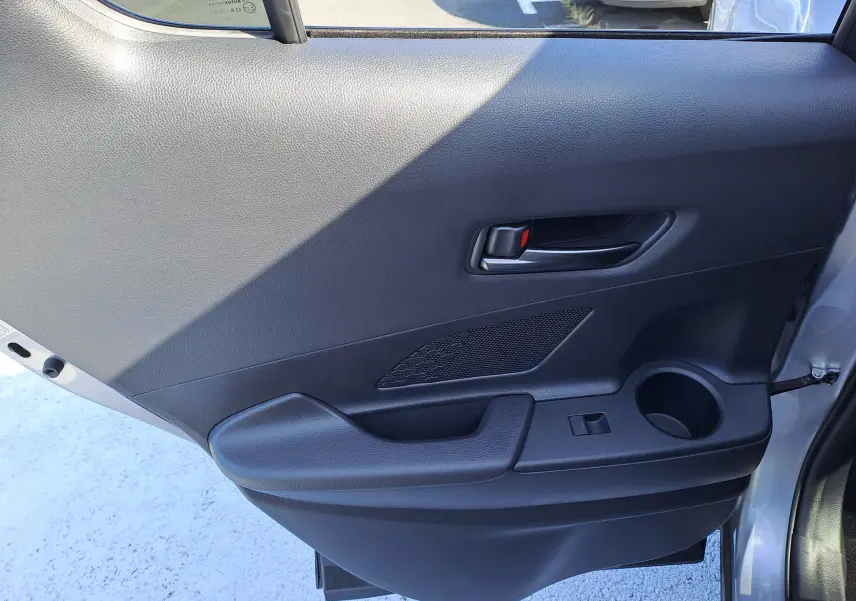 Coffre ouvert d'un Toyota C-HR gris minéral 2025, montrant un espace de rangement propre avec sac Toyota noir.