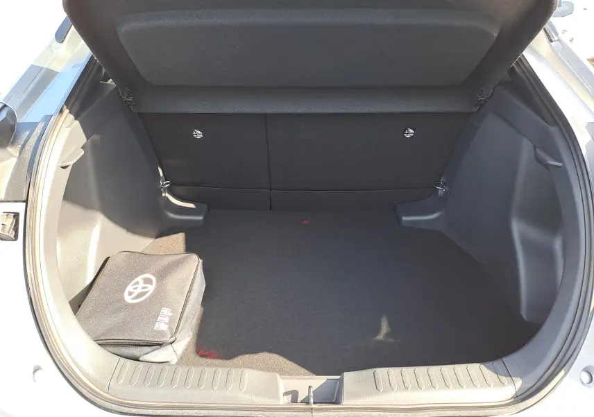 Coffre ouvert du Toyota C-HR gris minéral 2025 montrant le kit de réparation et les outils de secours rangés.