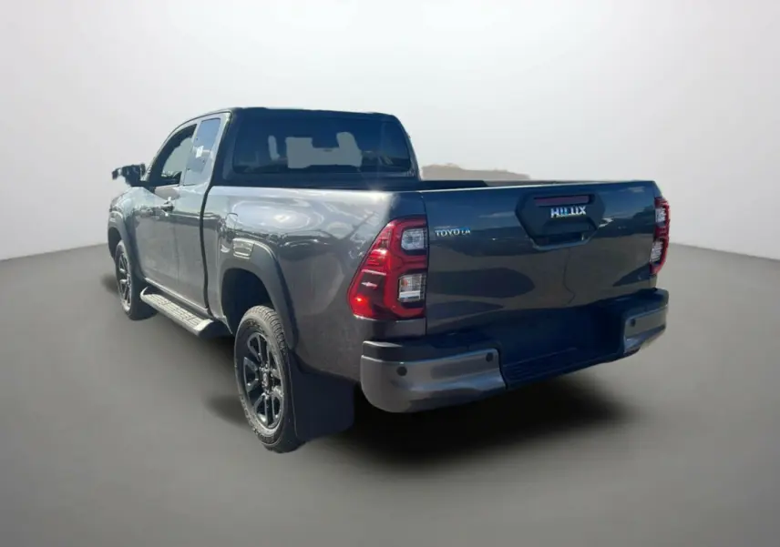Toyota Hilux 4x4 gris atlas 2025 vu en 3/4 arrière droit, avec hayon et feux arrière distinctifs rouges.
