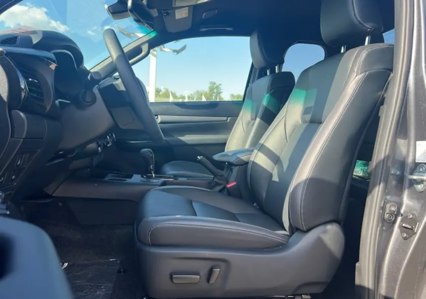 Intérieur du Toyota Hilux Invincible 2025, vue côté conducteur, sièges en cuir noir et tableau de bord moderne.