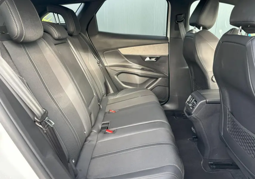 Vue latérale gauche de la banquette arrière noire en tissu et cuir du Peugeot 3008 2024, avec portes et aérateurs visibles.