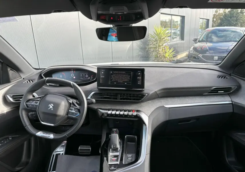 Vue intérieure avant du Peugeot 3008 2024, tableau de bord moderne avec écran tactile 10 pouces et volant compact cuir noir.