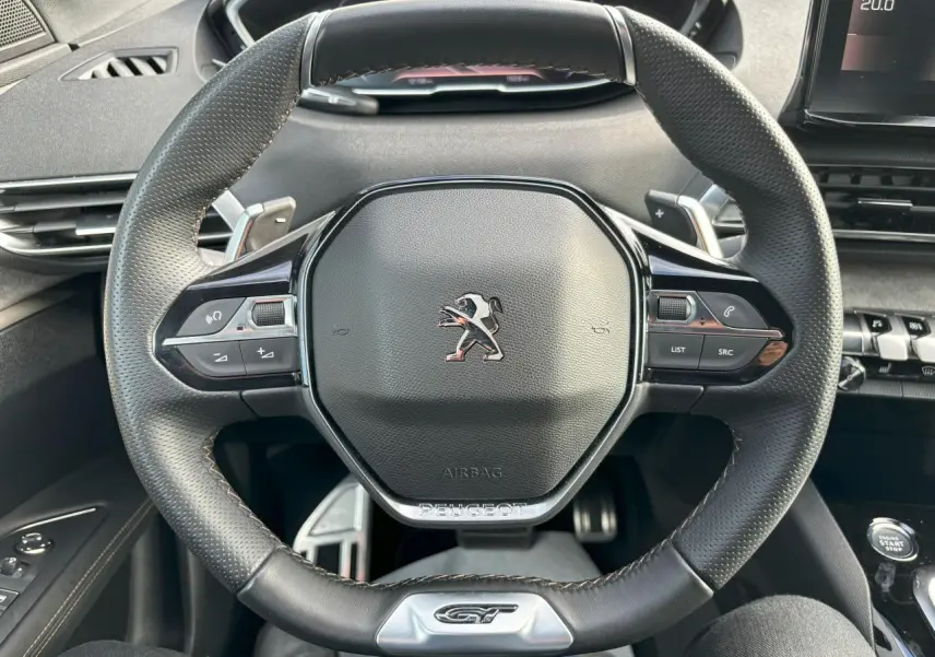 Vue rapprochée du volant cuir perforé noir avec badge GT et commandes multifonctions du Peugeot 3008 2024.