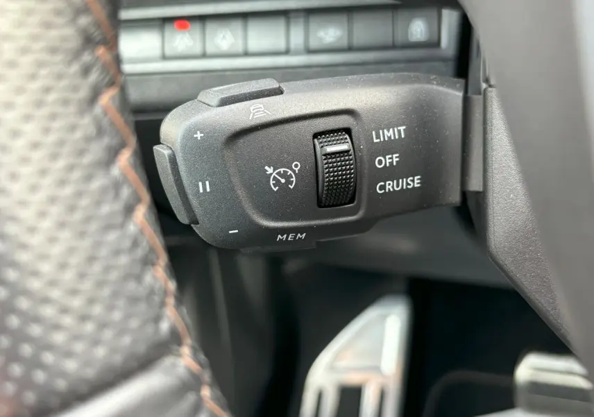 Gros plan sur la commande de régulateur de vitesse au volant cuir perforé du Peugeot 3008 blanc nacré 2024.