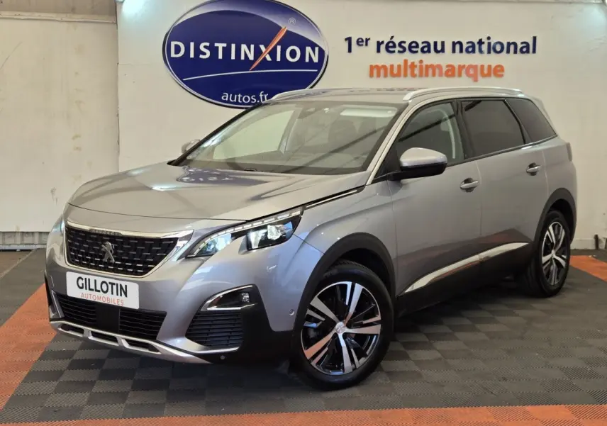 Peugeot 5008 gris clair vue 3/4 avant droit, avec jantes alliage bicolores et calandre distinctive noire.