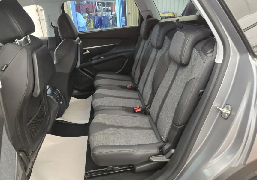 Vue latérale droite de l'intérieur du Peugeot 5008 gris clair, montrant la banquette arrière en tissu et cuir bicolore.