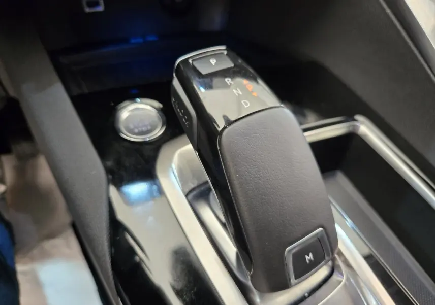 Gros plan sur la commande de boîte automatique noire du Peugeot 5008, avec bouton démarrage visible en arrière-plan.