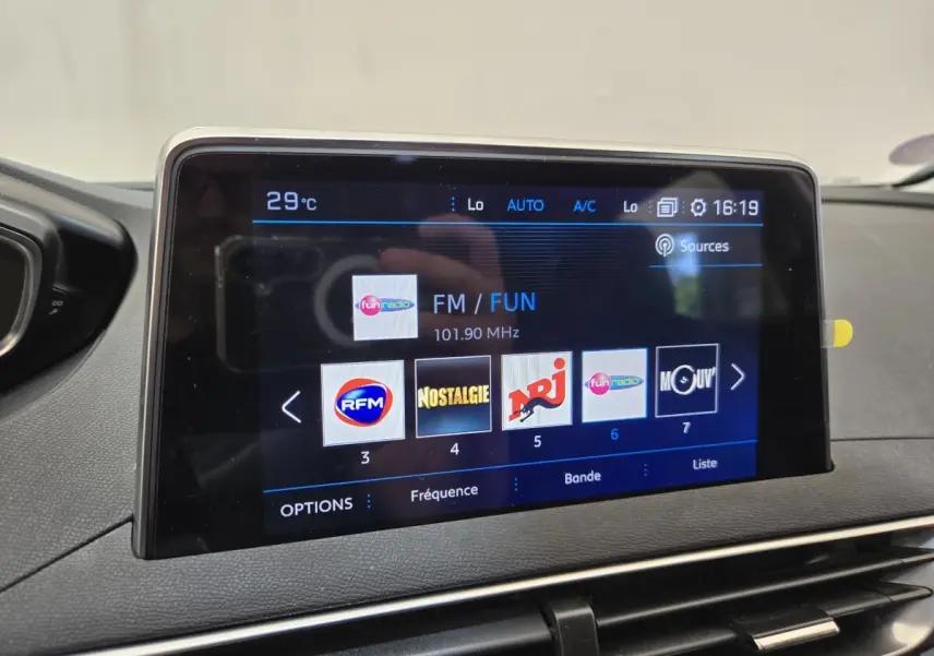 Écran tactile central du Peugeot 5008 gris clair affichant les stations radio FM avec interface moderne.