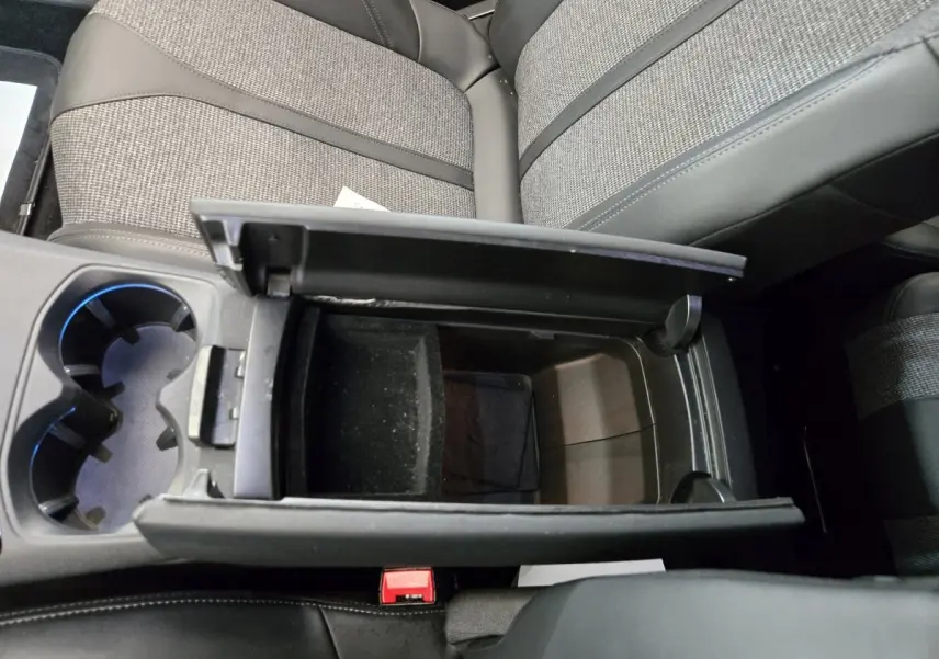 Vue plongeante sur la console centrale ouverte du Peugeot 5008 gris clair, avec porte-gobelets et sièges tissu et cuir.