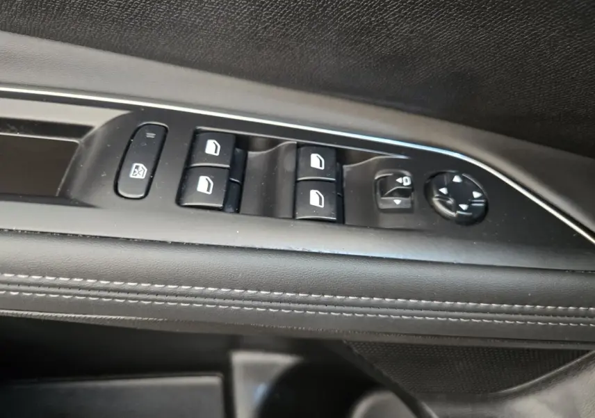 Détail des commandes de lève-vitres et réglage des rétroviseurs sur la porte intérieure noire du Peugeot 5008.