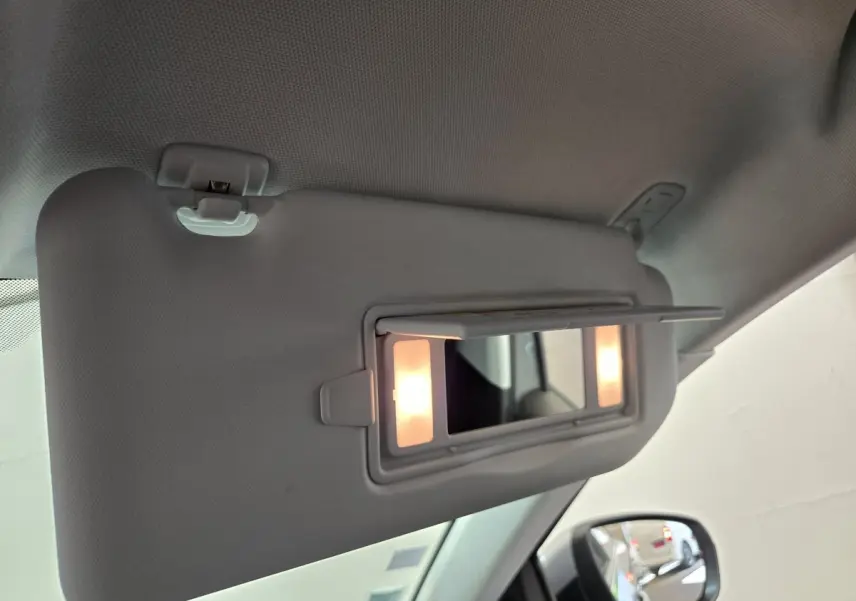 Miroir de courtoisie éclairé sur pare-soleil côté conducteur dans Peugeot 5008 gris clair, vue intérieure rapprochée.