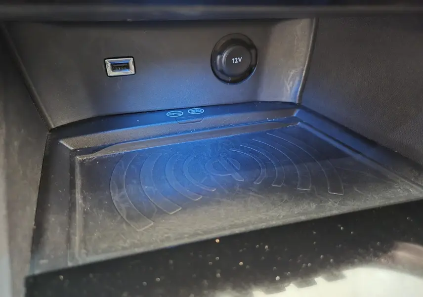 Gros plan sur la console centrale du Peugeot 5008 gris clair, montrant prise USB, prise 12V et zone de charge sans fil.