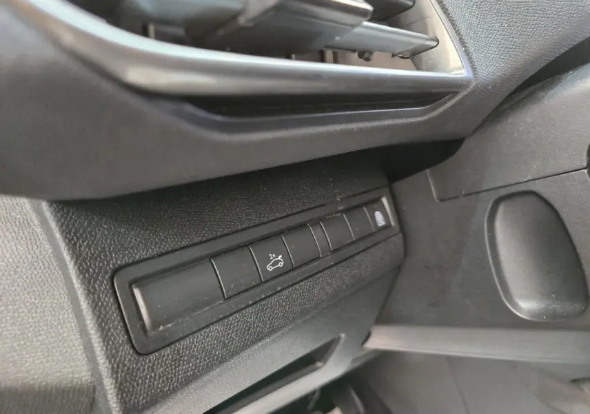 Détail intérieur côté gauche montrant les commandes d'ouverture du coffre et de verrouillage sur Peugeot 5008 gris clair.