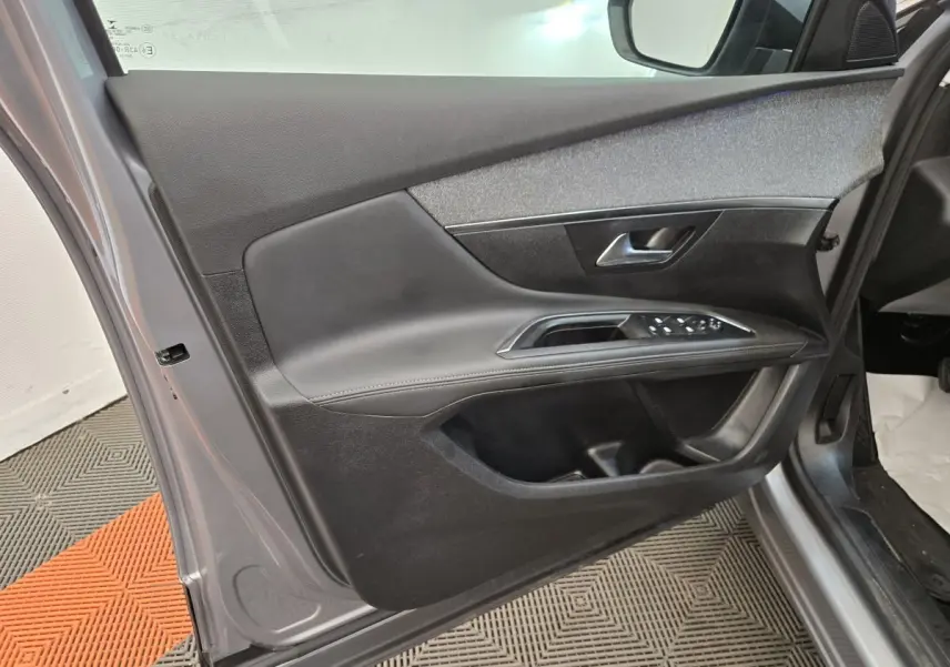 Vue intérieure de la porte avant gauche grise du Peugeot 5008 avec commandes de vitres et poignée métallique.