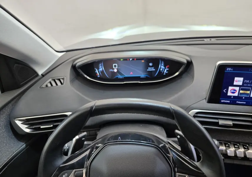 Vue intérieure centrée sur le volant cuir et le tableau de bord digital du Peugeot 5008 gris clair, version 2020.