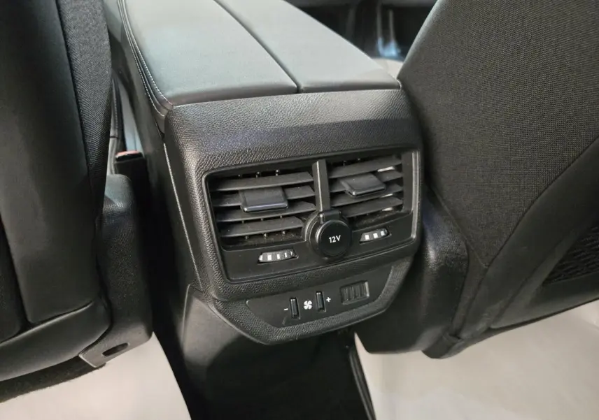 Vue rapprochée des commandes de ventilation arrière et prise 12V sur console centrale d’un Peugeot 5008 gris clair.