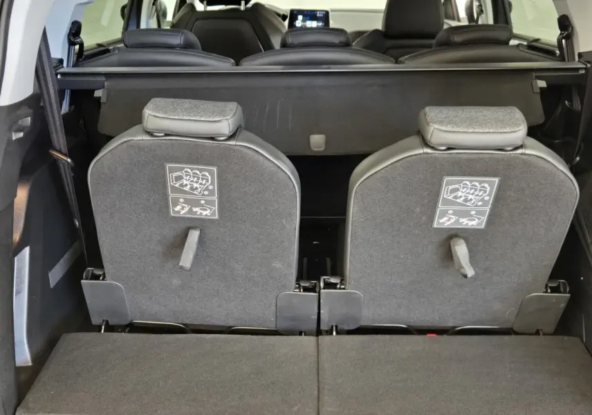 Vue arrière intérieure du coffre du Peugeot 5008 gris clair avec sièges arrière rabattus et tablette de coffre visible.