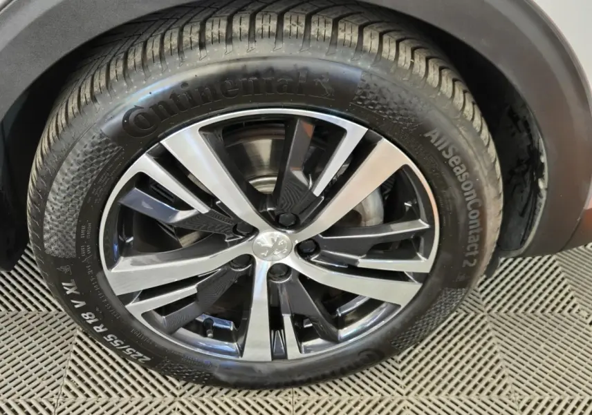 Gros plan sur la roue avant droite du Peugeot 5008 gris clair, avec jante alliage bicolore et pneu Continental.