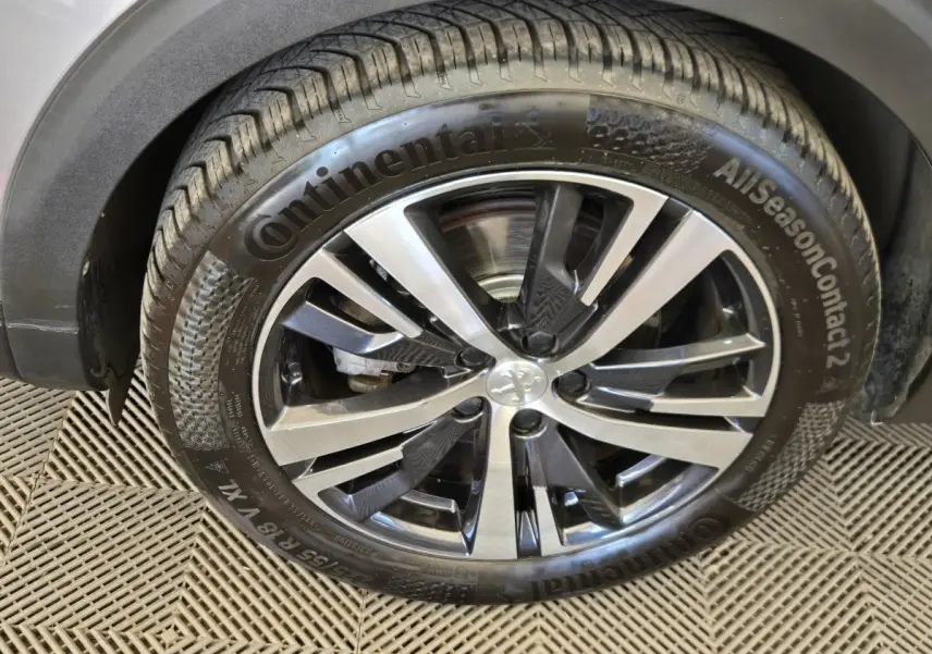 Gros plan sur la roue avant droite du Peugeot 5008 gris clair avec jante alliage et pneu Continental AllSeasonContact 2.