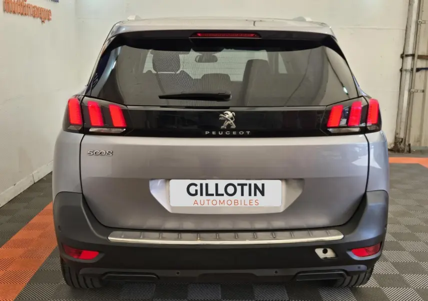 Vue arrière d'un Peugeot 5008 gris clair avec feux arrière LED caractéristiques et logo au centre du hayon.