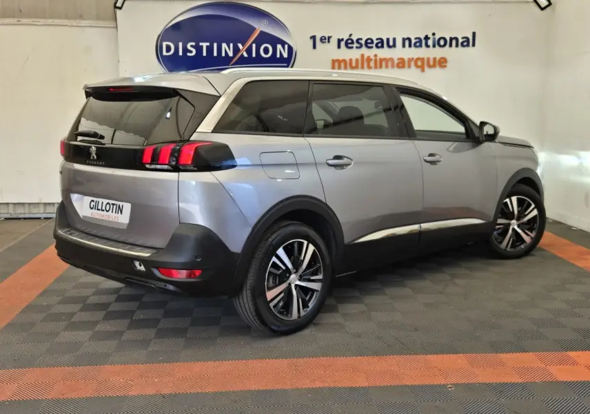 Peugeot 5008 gris clair vue 3/4 arrière droit, avec feux arrière LED et jantes alliage bicolores.