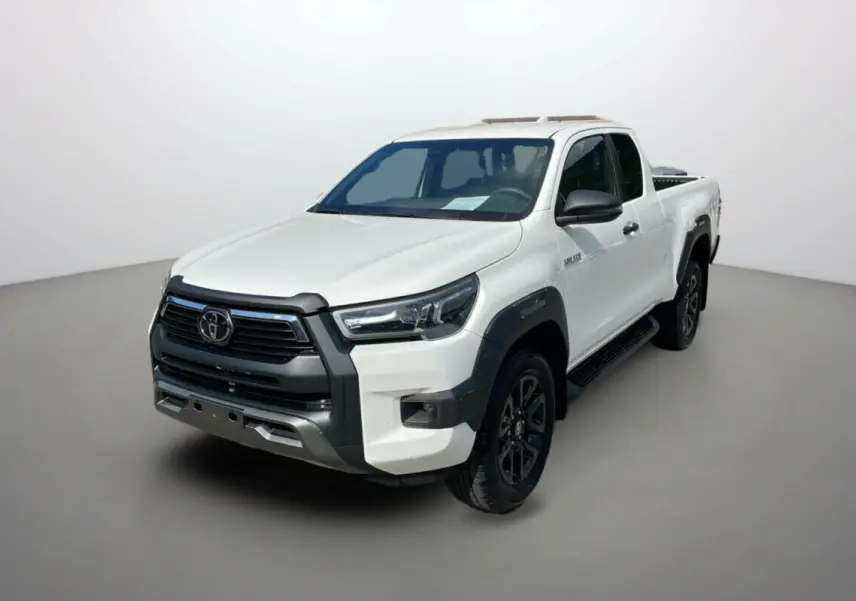 Toyota Hilux 4x4 blanc pur en vue 3/4 avant droit, avec calandre noire et jantes foncées distinctives.