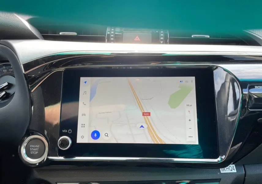 Vue rapprochée de l'écran tactile central et du bouton start/stop du Toyota Hilux 4x4 blanc pur 2025 Invincible.