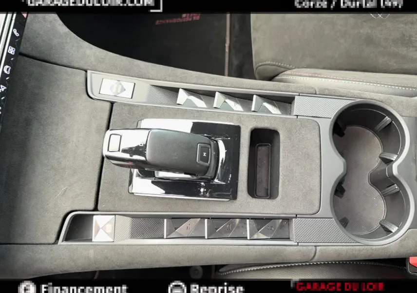 Vue plongeante sur la console centrale grise du DS7 Crossback blanc, mettant en valeur le levier de vitesse automatique et les boutons de commande.