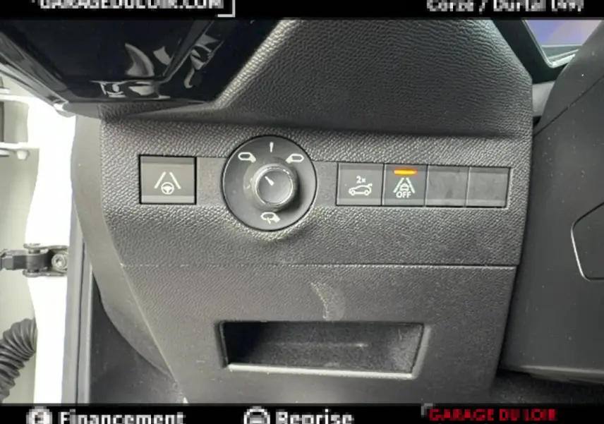 Gros plan sur les commandes noires du tableau de bord côté gauche du DS7 Crossback blanc, avec bouton d'ouverture coffre et régulateur.