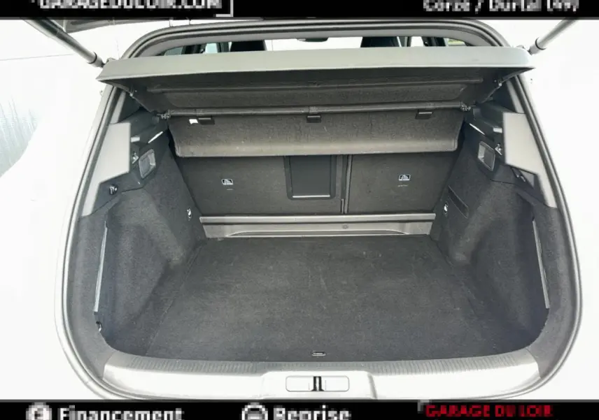 Coffre ouvert vu de l'arrière d'un DS7 Crossback blanc, espace de chargement vide et tapis noir.