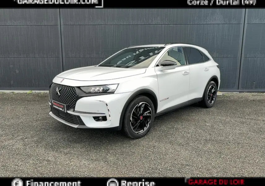 DS7 Crossback blanc en 3/4 avant droit, avec calandre noire distinctive et jantes noires brillantes.