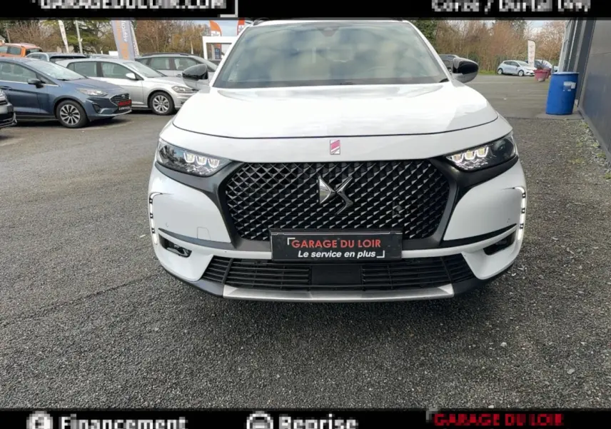 Vue avant frontale du DS7 Crossback blanc avec sa calandre noire distinctive et ses phares LED allumés.
