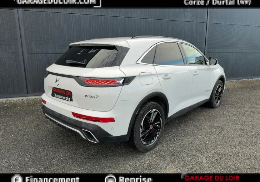 Vue 3/4 arrière droite d'un DS7 Crossback blanc avec jantes noires et feux arrière LED distinctifs.